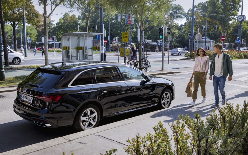 Mladi par &scaron;eće nogostupom i prolazi kraj vozila